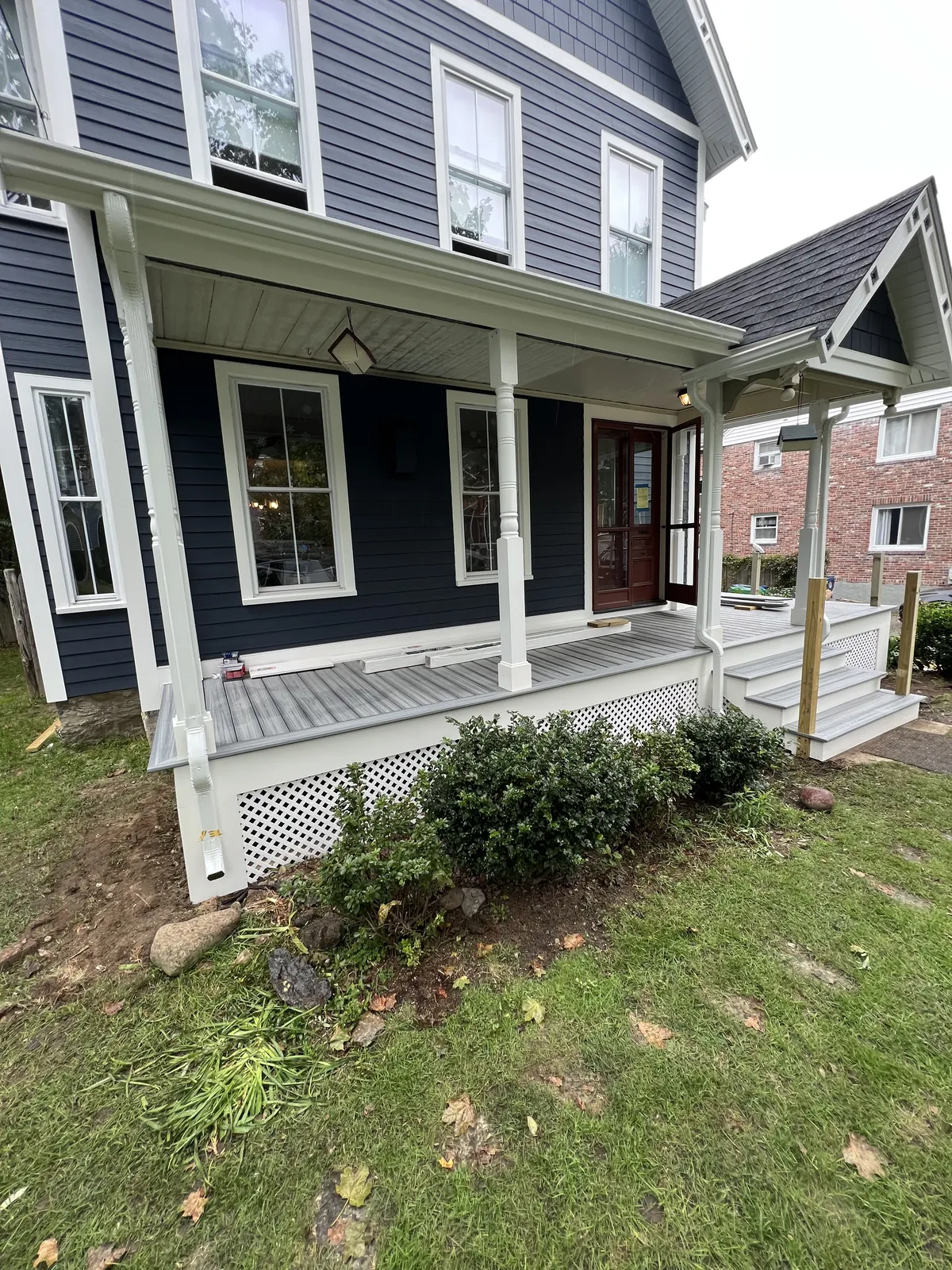 Completed farmer's porch with white railings and gray decking