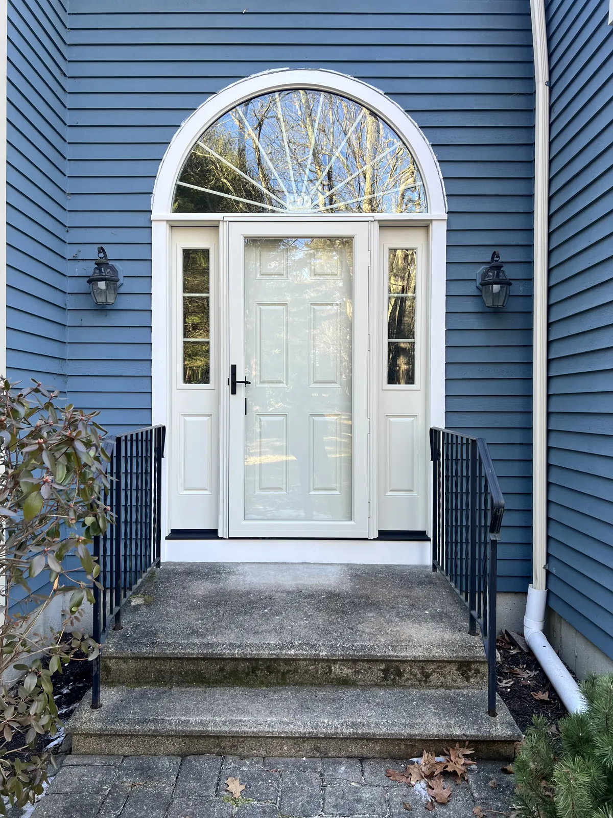 Arched transom entry door on a blue clapboard home